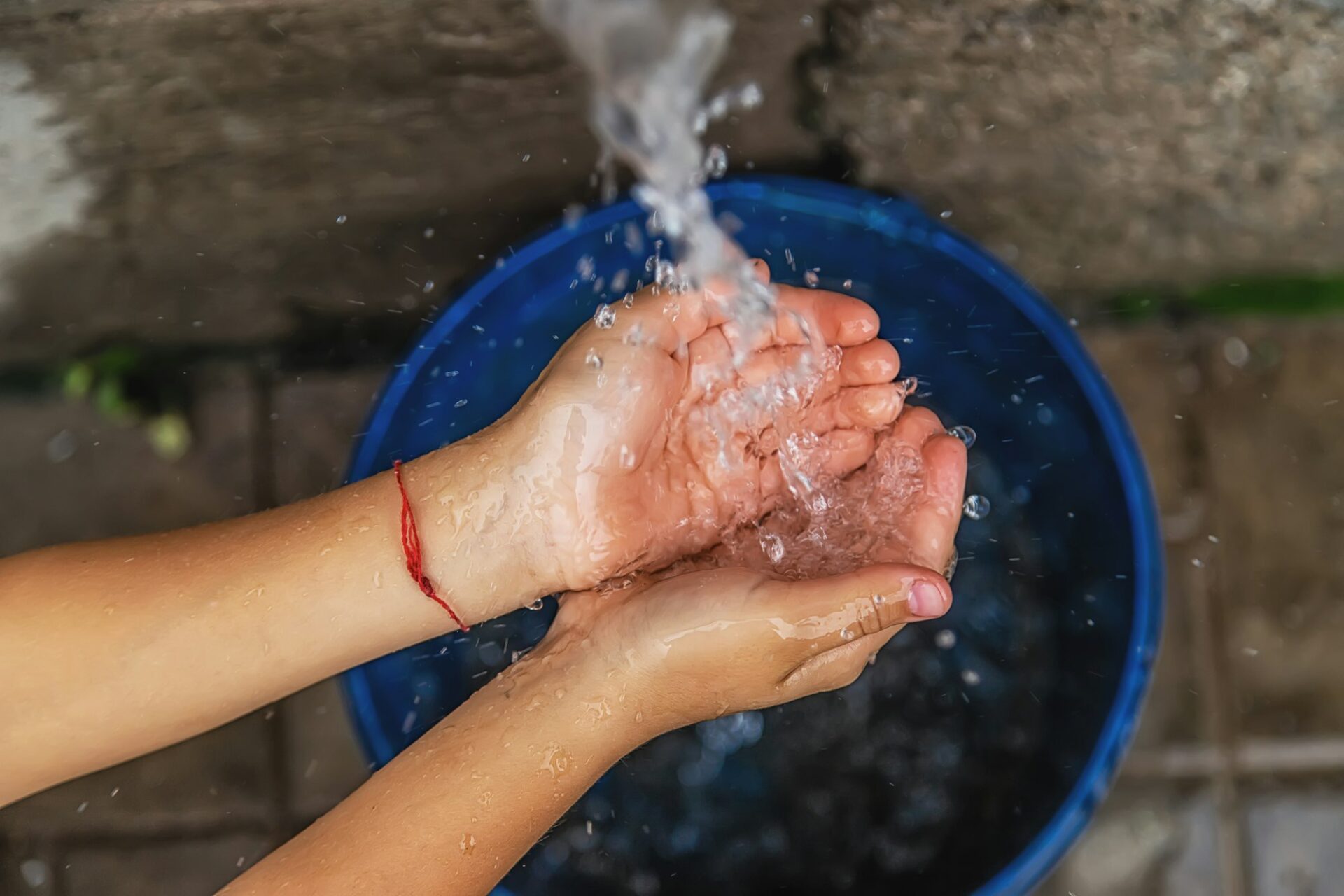 The water flows into the hands of the child. Selective focus.