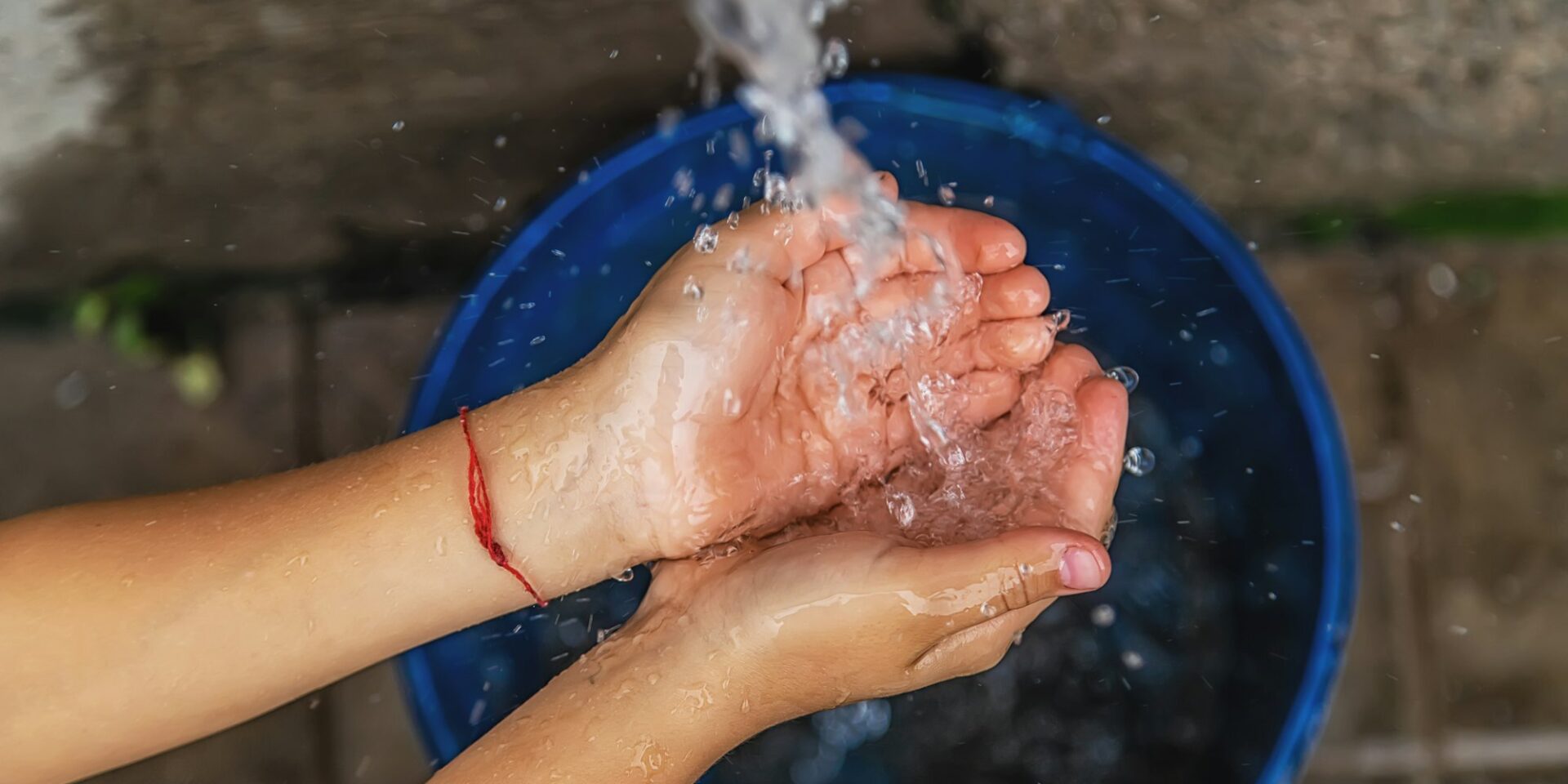 The water flows into the hands of the child. Selective focus.